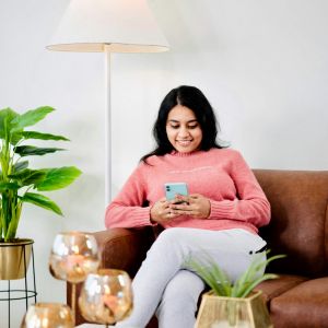 The Lodges of Huntersville A man paddles a red canoe across a serene lake surrounded by trees and mountains in the background.