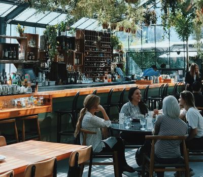 The Lodges of Huntersville A man paddles a red canoe across a serene lake surrounded by trees and mountains in the background.