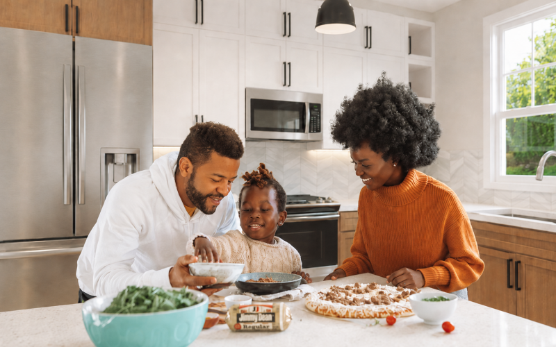 The Lodge of Huntersville A family collaborates in the kitchen, chopping vegetables and mixing ingredients for a meal.