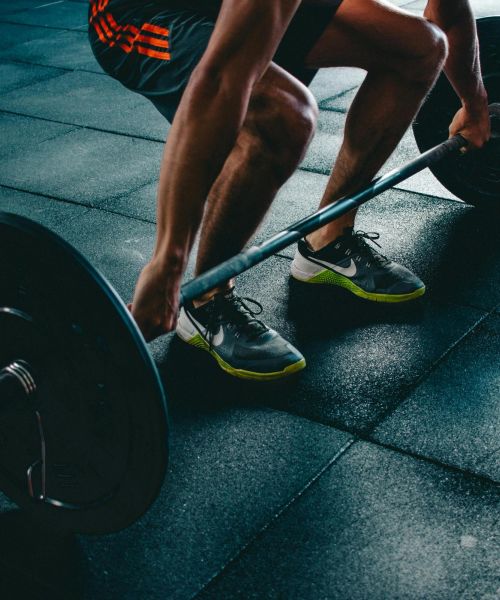 The Lodges of Huntersville A man squats with a barbell on his shoulders, focusing on his form in a gym setting.