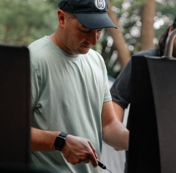 The Lodge of Huntersville A man wearing a stylish hat, standing outdoors with a neutral expression on his face.