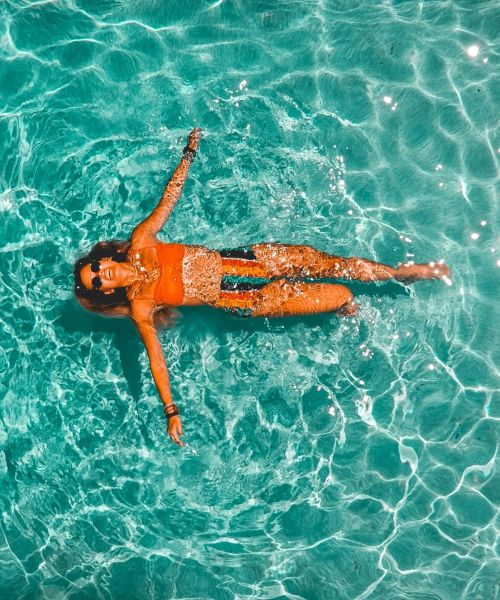 The Lodges of Huntersville A woman peacefully floating on her back in calm water, surrounded by a serene natural landscape.