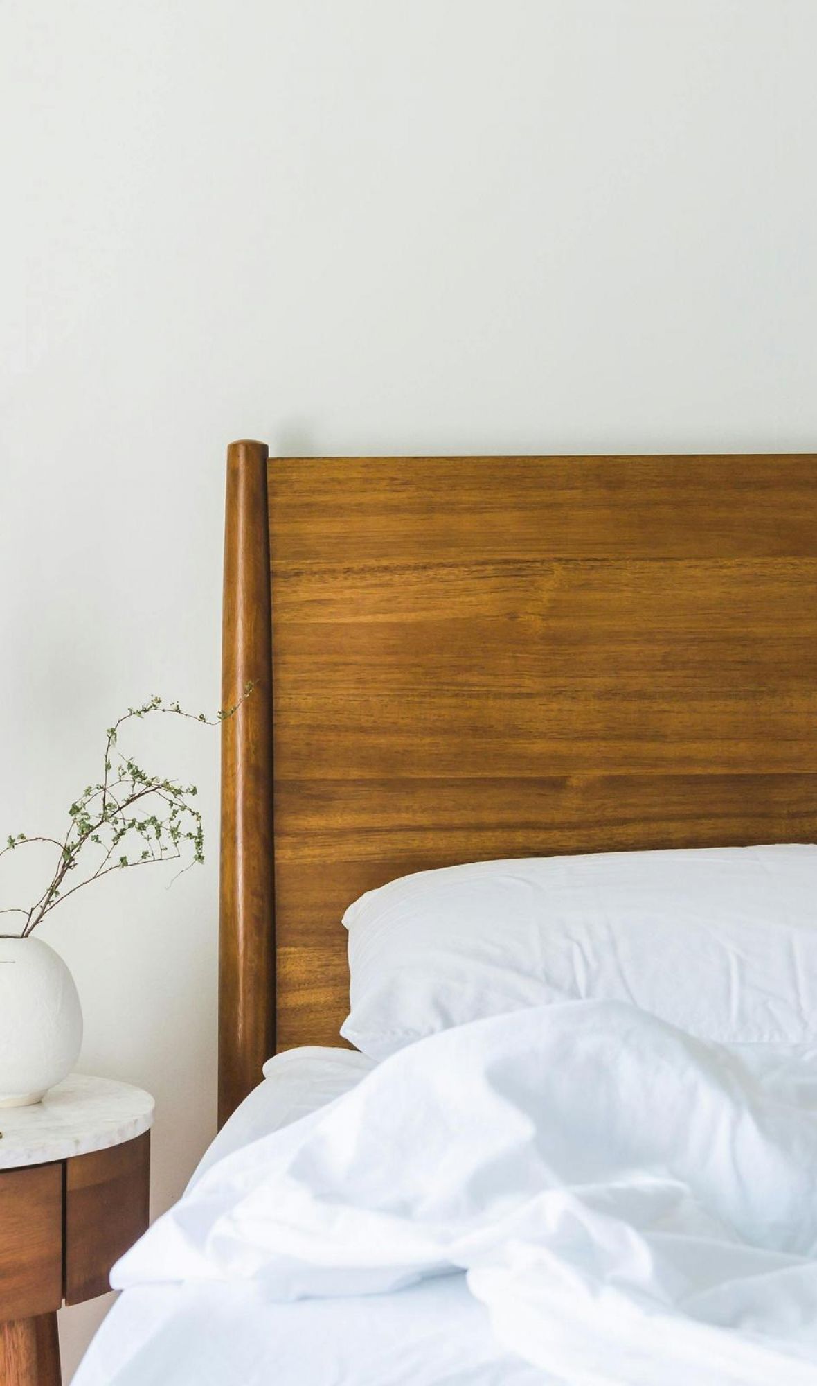 The Lodge of Huntersville 1. A neatly made bed featuring white sheets and a polished wooden headboard.