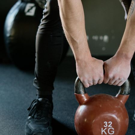 The Lodges of Huntersville 1. A person holds a kettlebell while standing in a gym, demonstrating strength training.