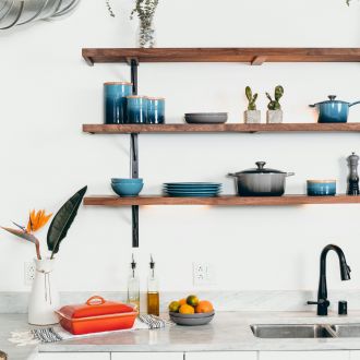 The Lodges of Huntersville A kitchen featuring a sink, stove, and shelves filled with kitchenware and ingredients.