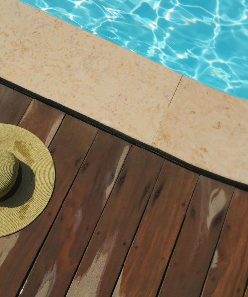 The Lodges of Huntersville A hat rests on a wooden deck beside a sparkling pool, capturing a relaxed summer atmosphere.