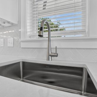 The Lodges of Huntersville A kitchen featuring a sink, stove, and shelves filled with kitchenware and ingredients.