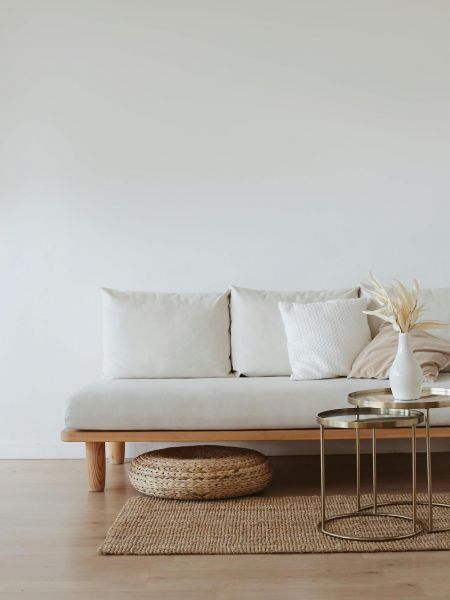 The Lodge of Huntersville A white couch positioned against a plain white wall in a minimalist room setting.