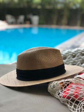 The Lodges of Huntersville A sun hat and a beach bag placed beside a sparkling pool, suggesting a relaxing day by the water.
